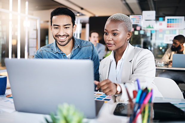 Coworkers collaborating on a laptop in a modern office.