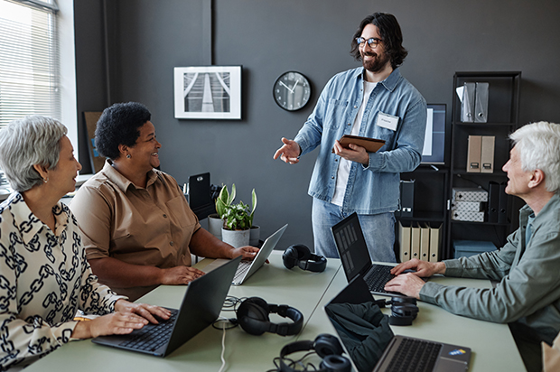 Team having a discussion around laptops in an office.
