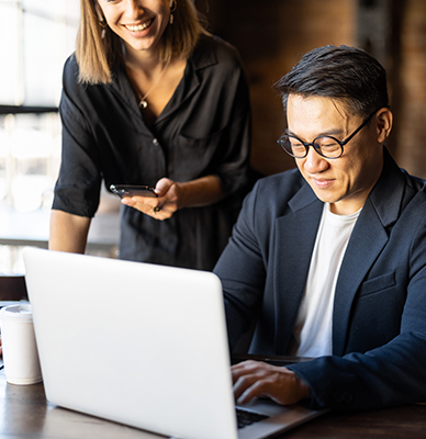 Smiling colleagues working together on a laptop.