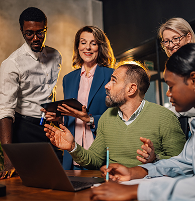 Team discussing a project while gathered around a laptop.