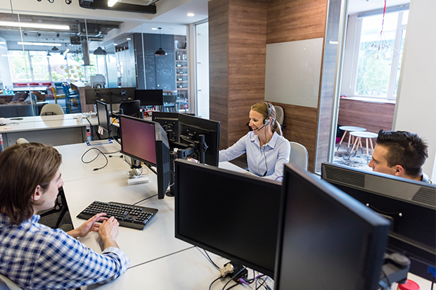 Customer support team working at desks with headsets.