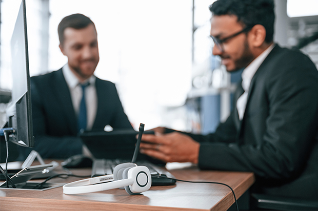 Two businessmen discussing work at an office desk.