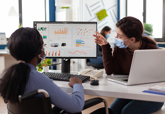 Colleagues discussing data charts on a computer screen.